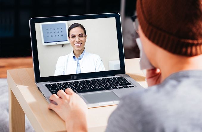 man talking with eye doctor on his laptop computer - telehealth