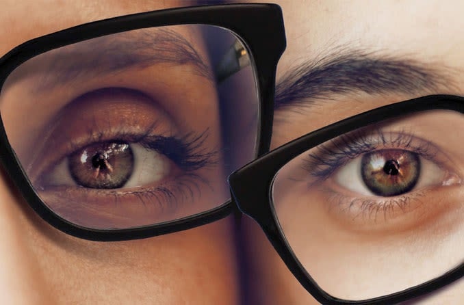 A hand holds a magnifying glass over the words &amp;quot;blurred vision,&amp;quot; which are above a background of many other symptoms of diabetes